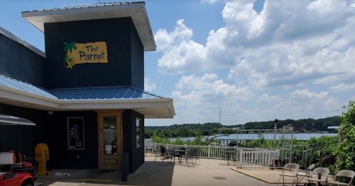 Exterior of The Parrot restaurant with a view of the water and cloudy sky, featuring outdoor seating.