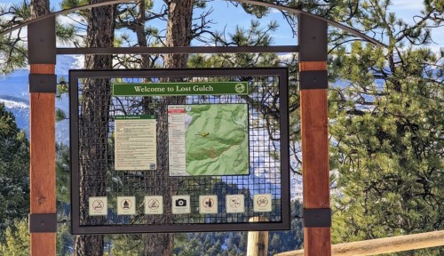 Sign at Lost Gulch with a map and information, surrounded by trees and mountains in the background.
