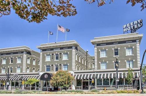 Historic Peery Hotel with flags, striped awning, and a clear blue sky in the background.
