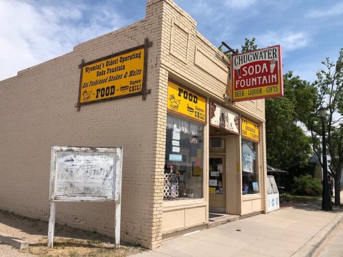 A vintage soda fountain shop with a sign for food, drinks, and gifts, located in Chugwater, Wyoming.