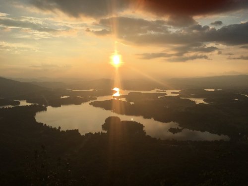 A stunning sunset over a lake, with rays of sunlight reflecting on the water and islands dotting the landscape.