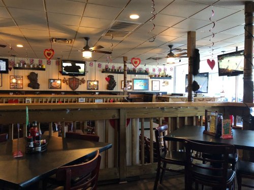Interior of a casual restaurant with wooden decor, tables, and festive heart decorations hanging from the ceiling.