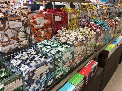 A colorful display of assorted candies in clear containers, arranged neatly on shelves.