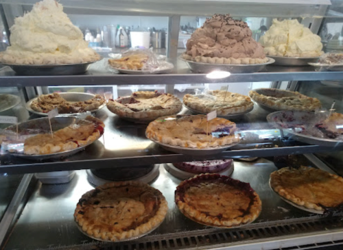 A display case filled with various pies and whipped cream desserts, showcasing a variety of flavors and toppings.