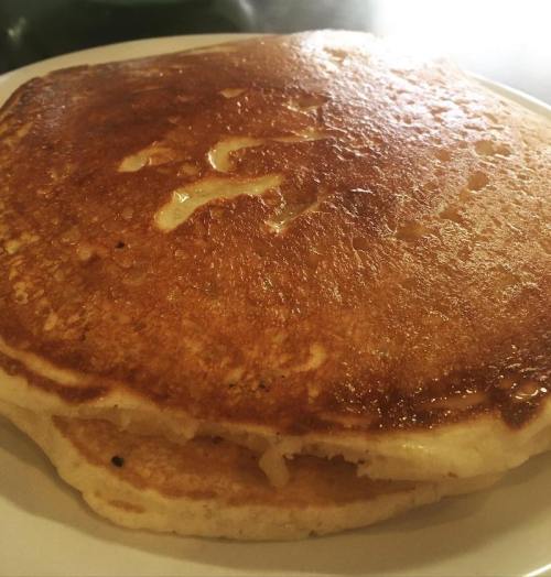 A golden-brown pancake on a white plate, with a slightly crispy surface and a fluffy interior.
