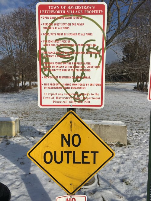 A sign with multiple warnings about property rules, including a "No Outlet" sign, in a snowy outdoor setting.