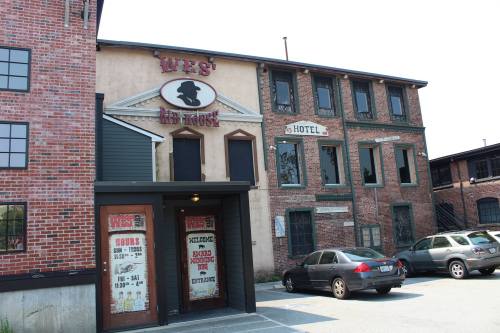 Exterior of a brick building with a sign reading "Wes' Inn House" and a parking lot in front.