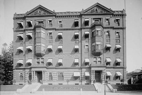 Historic brick building with ornate architecture, featuring multiple balconies and awnings, labeled "Rockingham."