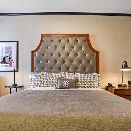 A stylish bedroom featuring a tufted headboard, decorative pillows, and bedside tables with lamps.