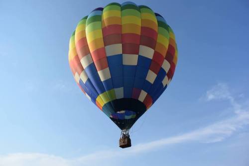 A colorful hot air balloon floats against a clear blue sky.