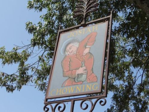 Sign for "Josiah Chowning" featuring a colorful illustration of a man in a red coat pouring a drink.