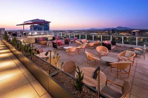 Rooftop lounge with stylish seating and a scenic view at sunset, featuring modern furniture and city skyline.