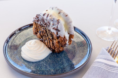 A dessert resembling a taco made of cookie, filled with ice cream and drizzled with chocolate, served with whipped cream.