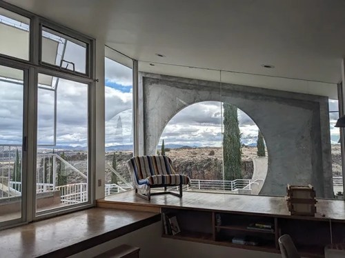 Modern interior with large windows showcasing a scenic view of trees and mountains under a cloudy sky.