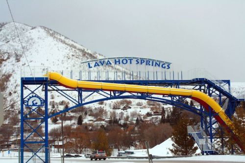 A colorful water slide at Lava Hot Springs, surrounded by snowy mountains and trees.