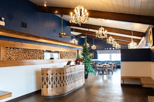 Interior of a restaurant featuring wooden decor, chandeliers, and a cozy dining area with a Christmas tree.