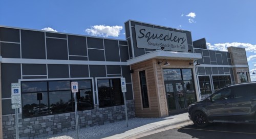 Exterior of Squealers Smoke Shack Bar & Grill, featuring a modern design with stone accents and large windows.