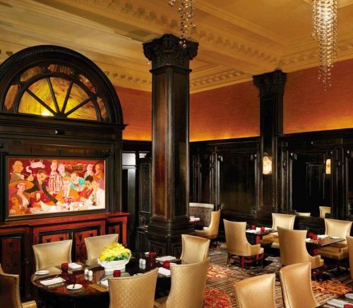 Elegant restaurant interior featuring dark wood accents, a colorful mural, and stylish seating arrangements.