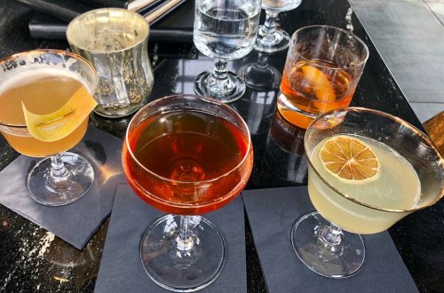 A variety of cocktails on a dark table, featuring different colors and garnishes in elegant glassware.