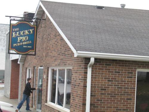 A boy approaches the entrance of The Lucky Pig Pub & Grill, a brick building with a sign above.