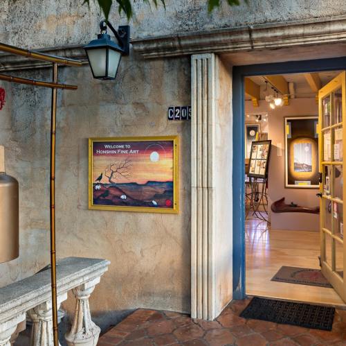 Entrance to Honshin Fine Art, featuring a welcoming sign and a view into the gallery with artwork displayed.