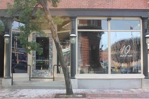 Exterior of a restaurant with a colorful door and large windows reflecting the street, surrounded by brick buildings.