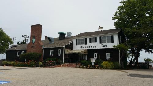 Exterior of Tuckahoe Inn, a two-story building with a brick chimney and a horse statue on the roof, surrounded by greenery.