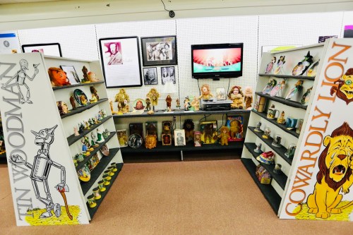Display of Wizard of Oz memorabilia featuring shelves with figurines and a TV showing related content.