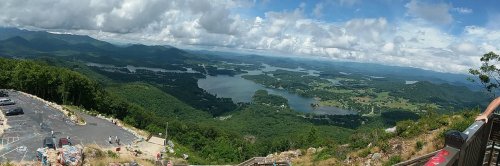 Panoramic view of lush green mountains and lakes under a partly cloudy sky. Scenic landscape from a high vantage point.