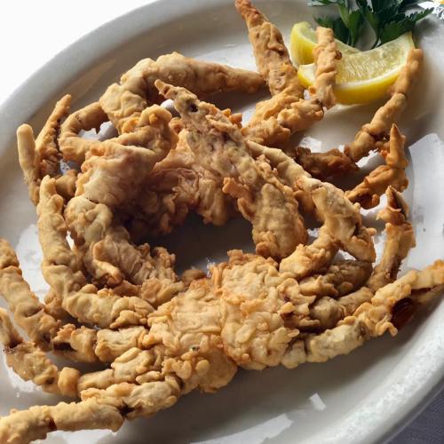 A plate of crispy fried soft-shell crabs garnished with a lemon wedge and parsley.