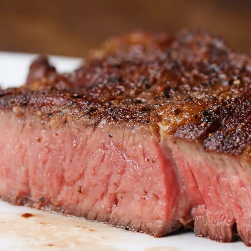 Close-up of a perfectly cooked steak, showcasing a juicy pink interior and a crispy, seasoned crust.