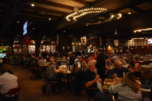 A bustling restaurant filled with diners at tables, featuring warm lighting and rustic decor.
