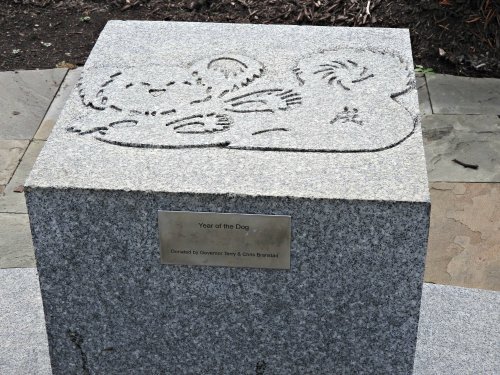 A granite pedestal with a carved design of a dog and a plaque reading "Year of the Dog."