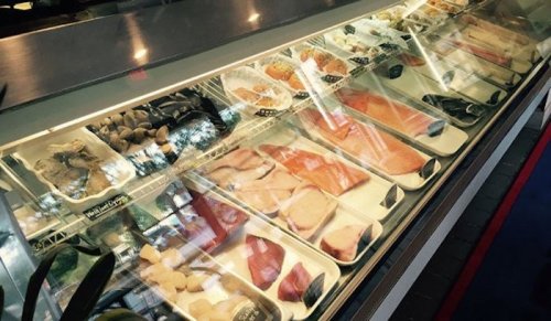 A display case filled with various types of fresh seafood, including fish fillets, shellfish, and other marine products.
