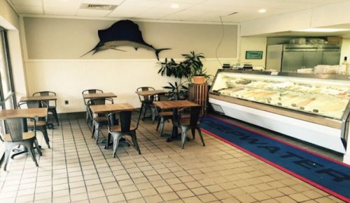 A cozy seafood restaurant interior with small tables, a display case, and a large fish mounted on the wall.