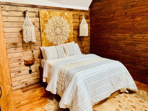 Cozy bedroom with a wooden accent wall, a bed with striped bedding, and decorative macramé wall hangings.