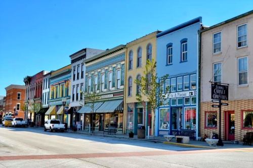 Colorful storefronts line a sunny street, showcasing a mix of architectural styles and vibrant facades.