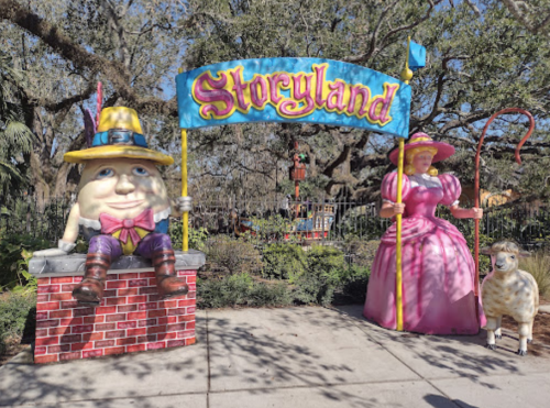 Colorful entrance to Storyland featuring Humpty Dumpty, a princess, and a sheep, surrounded by trees.