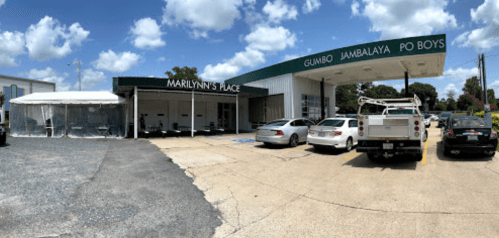 Exterior view of Marilynn's Place, a restaurant featuring a covered patio and signage for gumbo, jambalaya, and po boys.