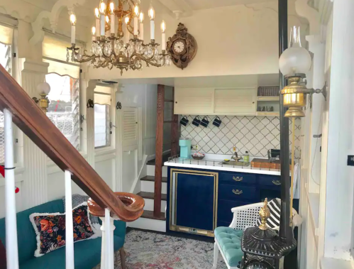 Cozy interior featuring a chandelier, vintage decor, a kitchen area, and a staircase in a charming space.