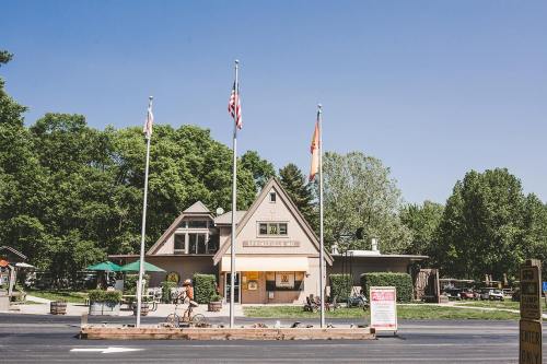 A triangular building with flags in front, surrounded by trees and outdoor seating on a sunny day.
