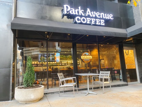 Exterior of Park Avenue Coffee with a sign, outdoor seating, and a welcoming atmosphere.