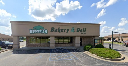 Exterior of Hoecklee's Bakery & Deli building with a sign, blue sky, and clouds in the background.