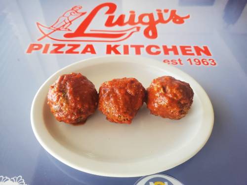 Three meatballs in marinara sauce on a white plate, with a "Luigi's Pizza Kitchen" logo in the background.