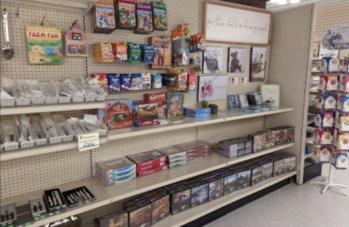 A store shelf displaying various puzzles, games, and craft supplies, with a sign reading "Art for Kids & Teens."