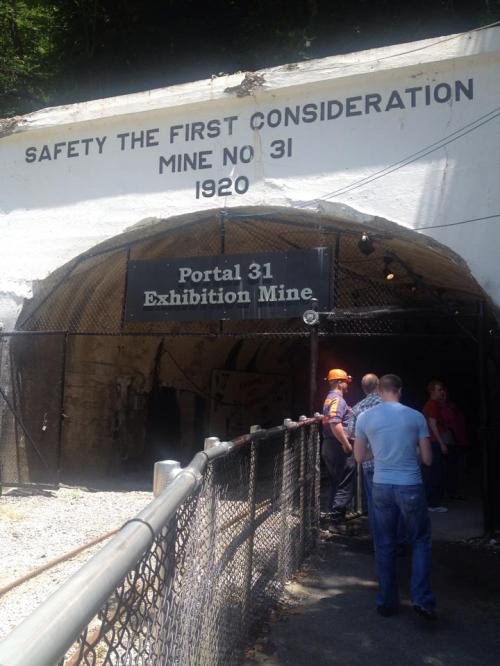 Entrance to Portal 31 Exhibition Mine, with a sign reading "Safety the First Consideration" and visitors nearby.