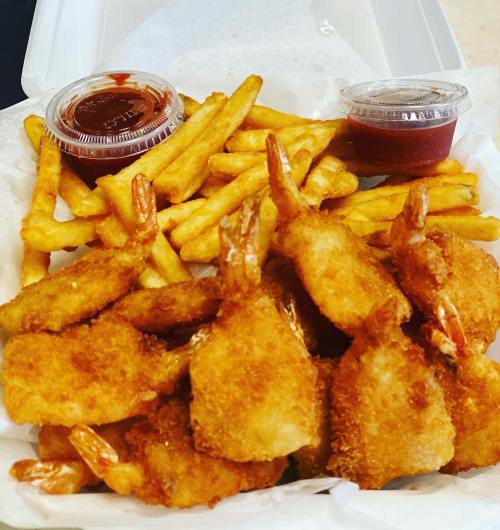A takeout container filled with golden fried shrimp, crispy fries, and two cups of dipping sauce.