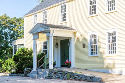 A yellow colonial-style building with a welcoming entrance and stone steps, surrounded by greenery.