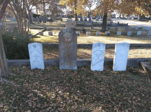 Gravestones in a cemetery surrounded by autumn leaves and trees, with a peaceful, serene atmosphere.