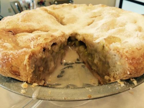 A freshly baked pie with a golden crust, showing a gooey filling and sprinkled with sugar on top.